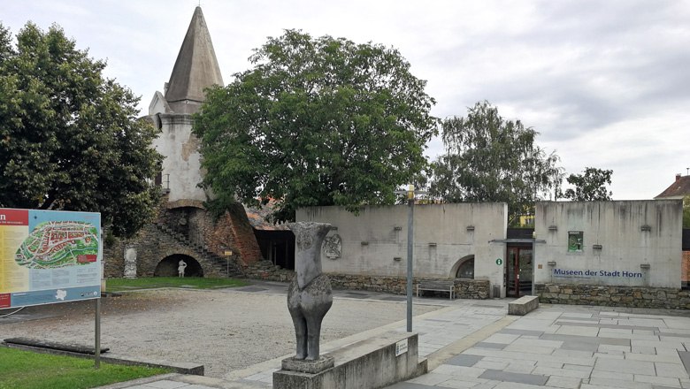 Stadtmauer und Museum in Horn mit Statue und Infotafel im Vordergrund.