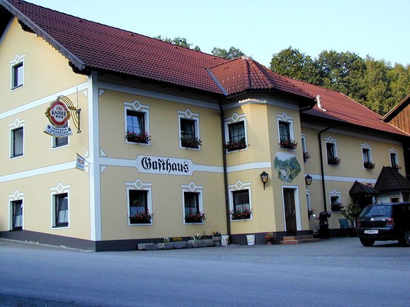 Ein traditionelles Gasthaus mit gelber Fassade und roten Dachziegeln.