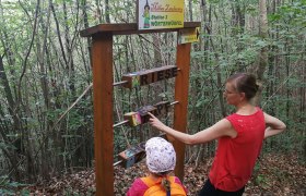 Zwei Personen an einer Station im Wald mit Wortwürfeln auf Millas Zauberweg.