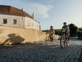 Ein Mann und eine Frau radeln bergauf entlang der Stadtmauer