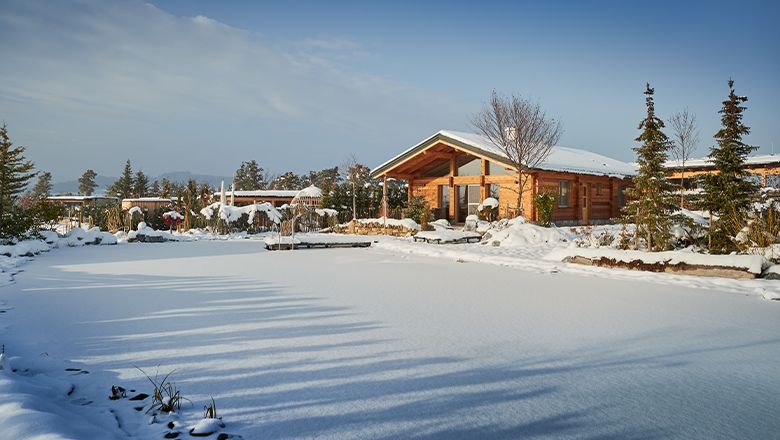 Verschneite Chalets am Gartensee mit winterlicher Landschaft.