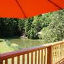 View of a pond and forest from a terrace with a red parasol.