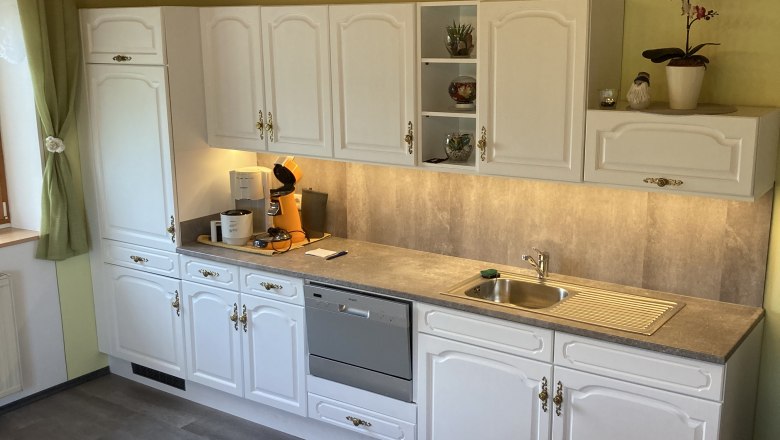 Küche mit weißen Schränken, Geschirrspüler und Spüle.