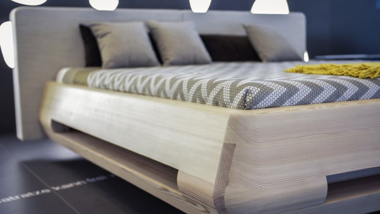 Modernes Bett mit Holzrahmen und gemustertem Bettbezug.