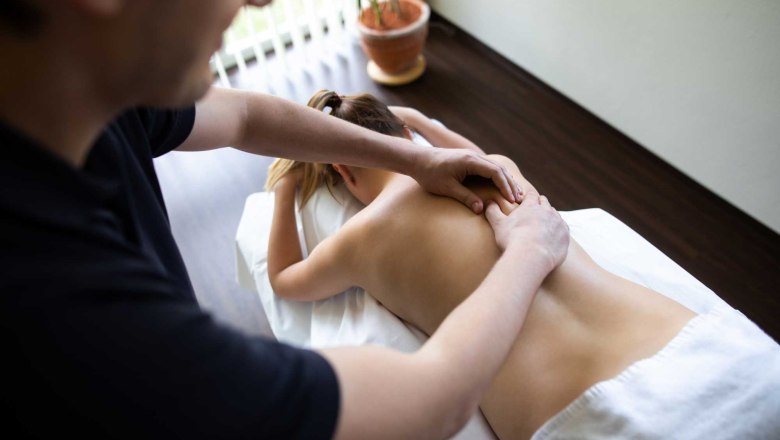 Person erhält eine Rückenmassage auf einem Massagetisch.