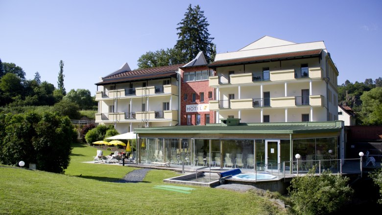 Exterior view of a hotel with garden and pool area.