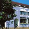 Gasthof Großmann mit blauer Fassade und Baum im Vordergrund.