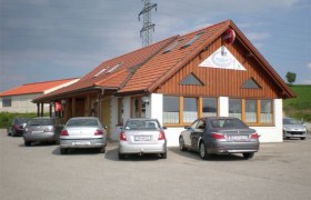 Ein Restaurant mit Holzfassade und mehreren geparkten Autos davor.
