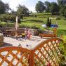 Garten mit Terrasse, Spielplatz und grüner Wiese im Hintergrund.