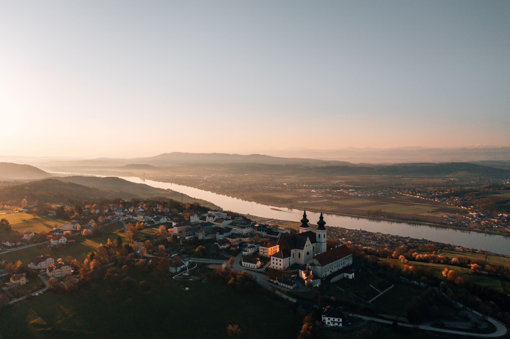 Luftaufnahme von Maria Taferl mit der Donau im Hintergrund bei Sonnenuntergang.