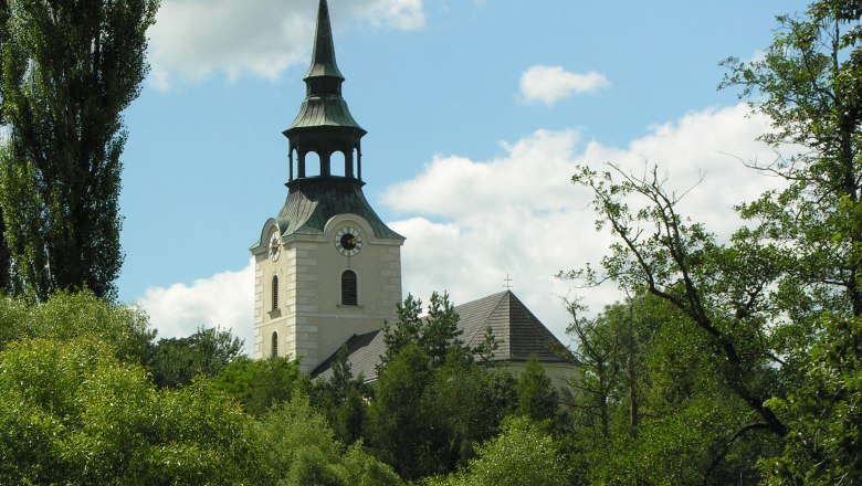 Church tower in Dobersberg surrounded by trees and blue sky.