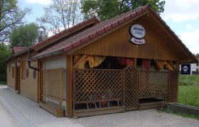 Holzgebäude mit Schild 'Mühlbachstüberl' und 'Zwettler' Logo, umgeben von Bäumen.