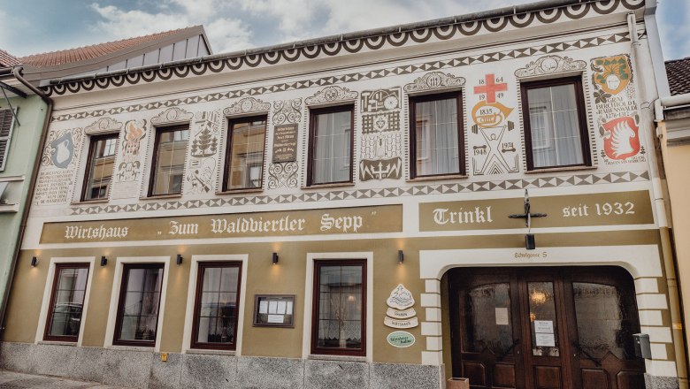 Fassade eines traditionellen Wirtshauses mit dekorativen Malereien und Schriftzug "Zum Waldviertler Sepp" in Schrems.