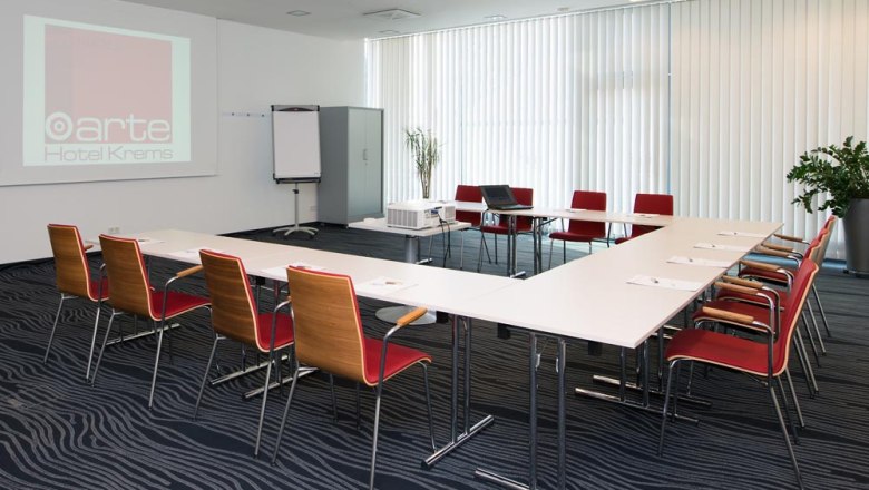 Konferenzraum im arte Hotel Krems mit Tischen, Stühlen und Präsentationstechnik.