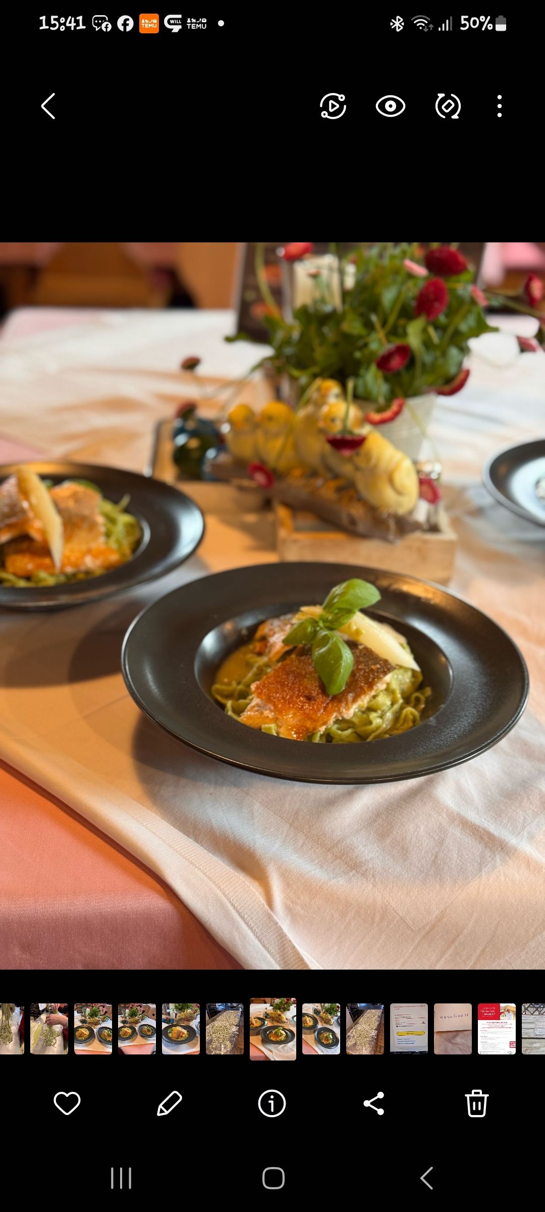 Zwei Teller mit Fisch und Pasta auf einem Tisch, dekoriert mit Blumen.