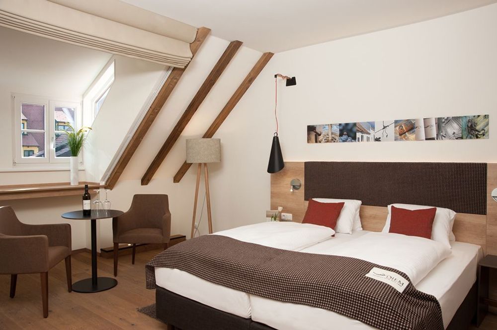 Gemütliches Hotelzimmer mit Doppelbett, Sitzbereich und Dachschräge.