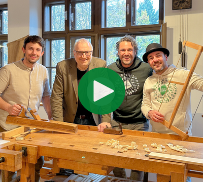 4 Personen in einer traditionellen Tischlerei lachend mit Utensilien in die Kamera