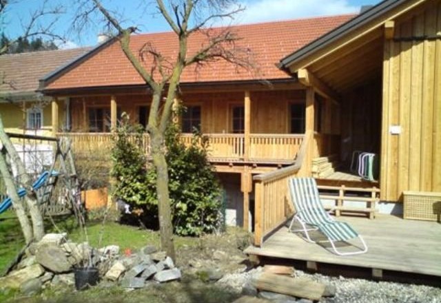 Holzgebäude mit Terrasse und Garten im Vordergrund.