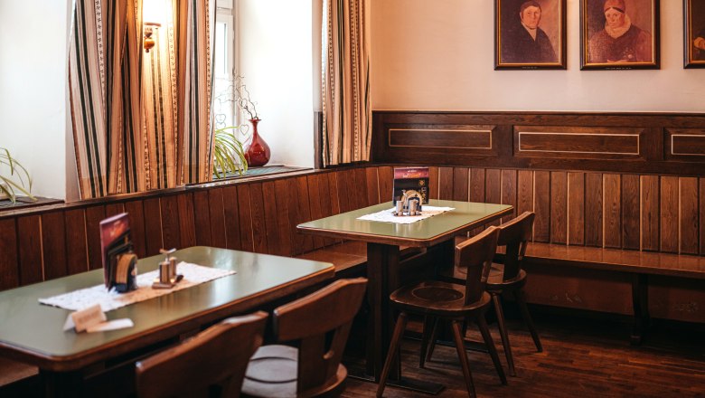 Traditionelle Stube mit Holzm&ouml;beln und Gem&auml;lden an der Wand.