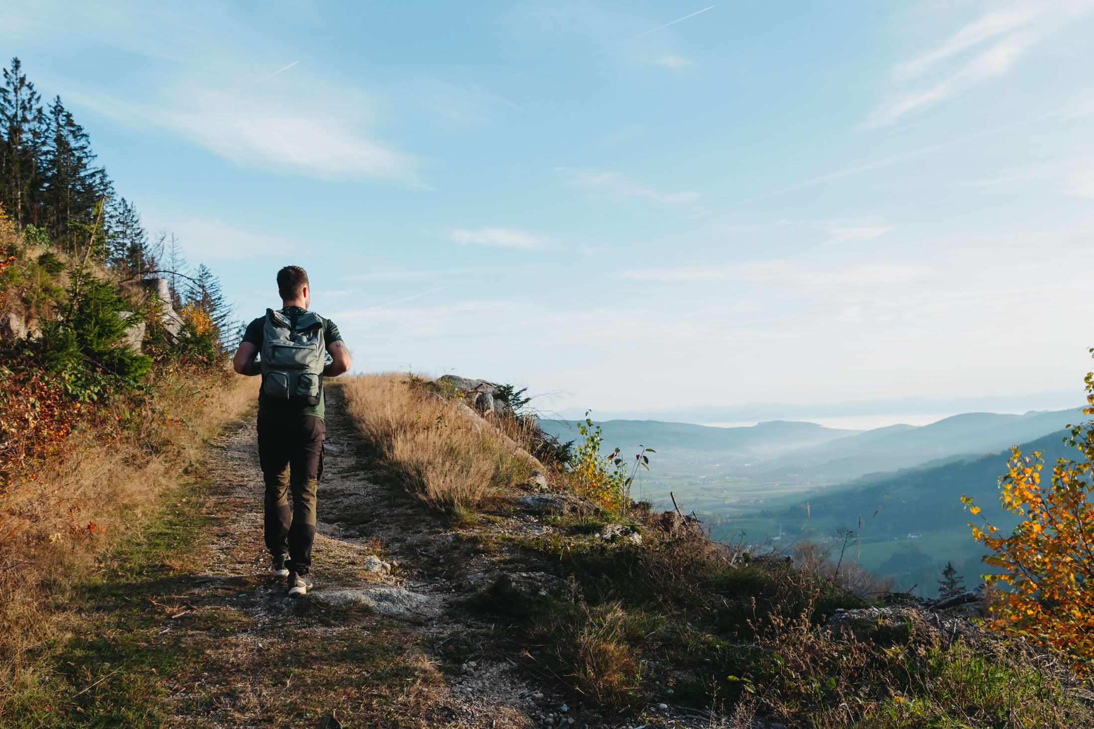Mann mit Rucksack wandert auf einem sanften Hügel