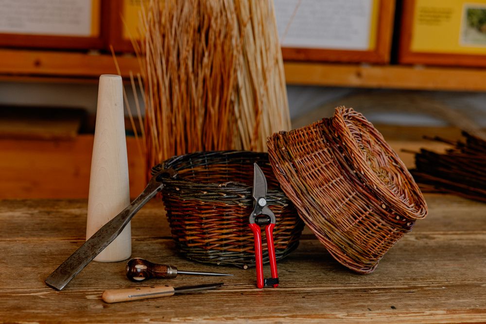 Werkzeuge und geflochtene Körbe auf einem Holztisch in einer Werkstatt.