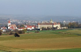 Landschaft mit Kirche und Schloss in der Ferne.