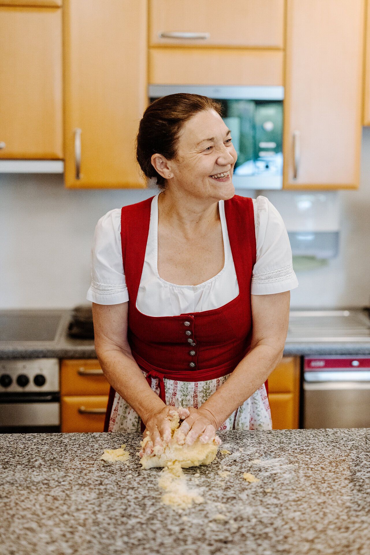 In einer einladenden Küche wird mit viel Freude und Geschick an köstlichen Mohnnudeln gearbeitet. Die warme Atmosphäre und das Lächeln der Mohnwirtin schaffen eine perfekte Kulisse für einen unvergesslichen Kochkurs.