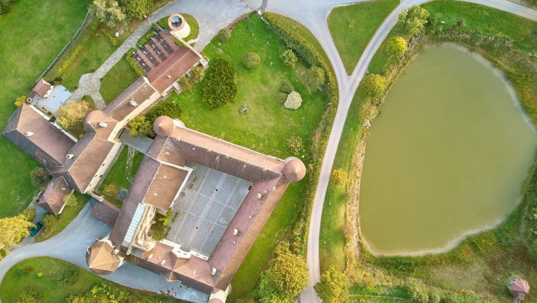Luftaufnahme von Schloss Waldreichs mit umliegendem Park und Teich.