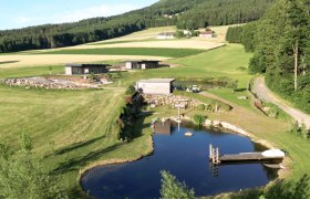 Landschaft mit Teich, Wiese und Peilstein im Hintergrund.