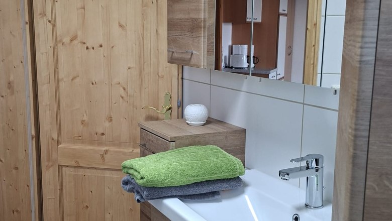 Badezimmer mit Holzschränken, Waschbecken und Handtüchern.