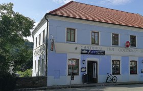 Ein zweistöckiges Gebäude mit der Aufschrift 'Gasthaus zum Goldenen Stern' und einem Fahrrad davor.