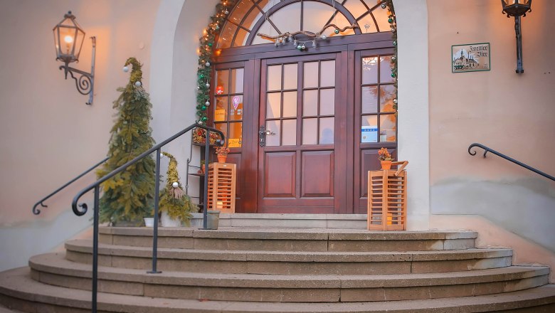 Eingang mit dekorierten Weihnachtsbäumen und Lichtern.