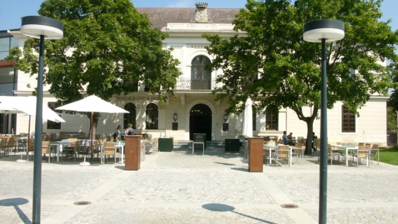 Außenansicht der Taverne im Schloss Grafenegg mit Tischen und Sonnenschirmen auf dem Vorplatz.