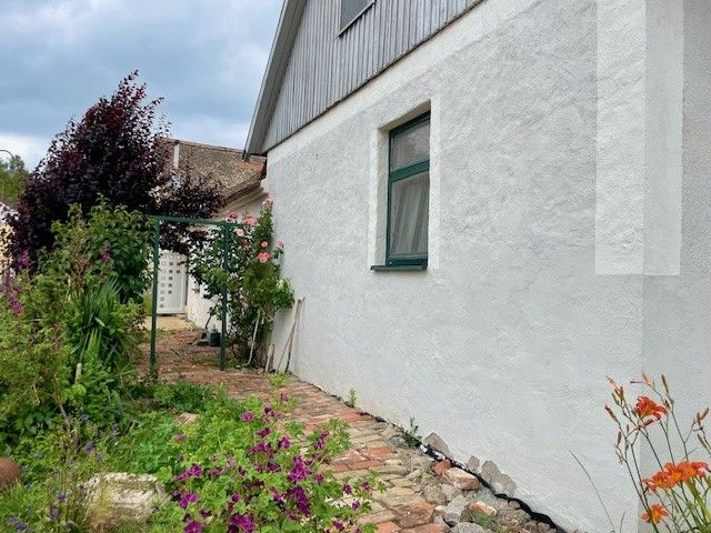 Außenansicht eines Hauses mit weißer Wand, Garten und Blumen.