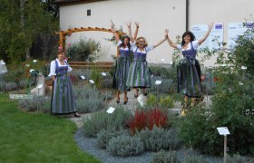 Frauen in Dirndln springen in einem Lavendelfeld.
