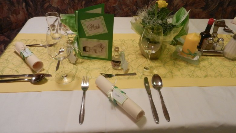 Festlich gedeckter Tisch mit Menükarte, Besteck, Gläsern und Dekoration.