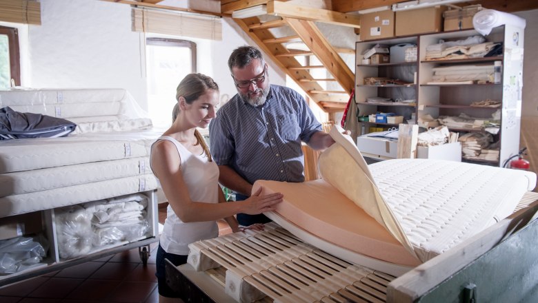 Two people in a workshop inspecting a mattress.