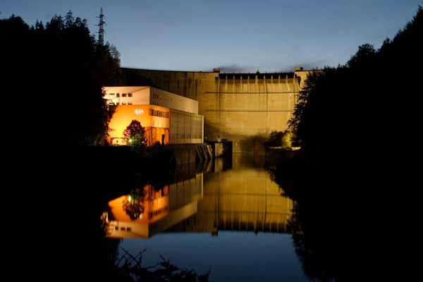 Nachtaufnahme des beleuchteten Kraftwerks Ottenstein mit Spiegelung im Wasser.