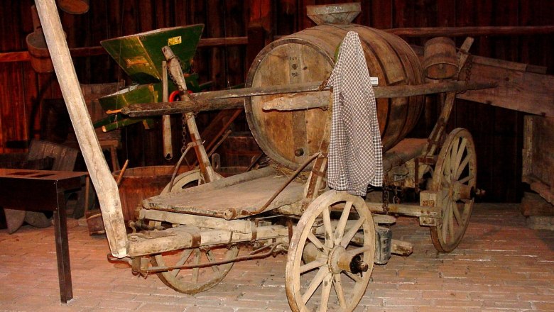 Alte Holzkutsche mit Fass in einem Museum.