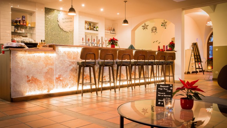 Elegante Bar mit beleuchtetem Tresen und hohen Stühlen, dekoriert mit Weihnachtssternen.