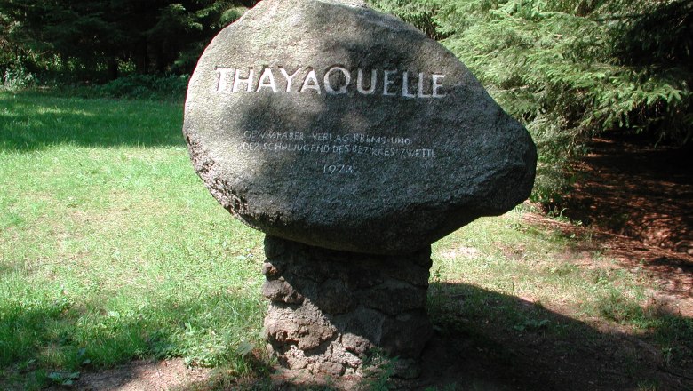 Ein Gedenkstein mit der Aufschrift 'Thayaquelle' im Wald.