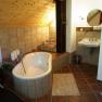 Rustic bathroom with bathtub, washbasin and wooden ceiling.