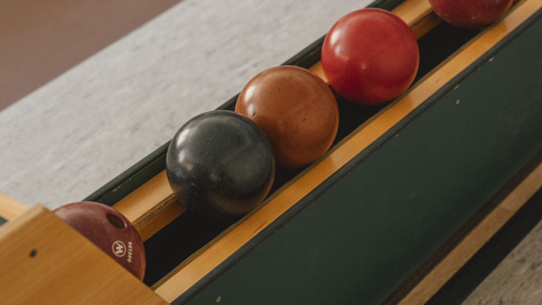 Skittle alley with four skittle balls in a holder.