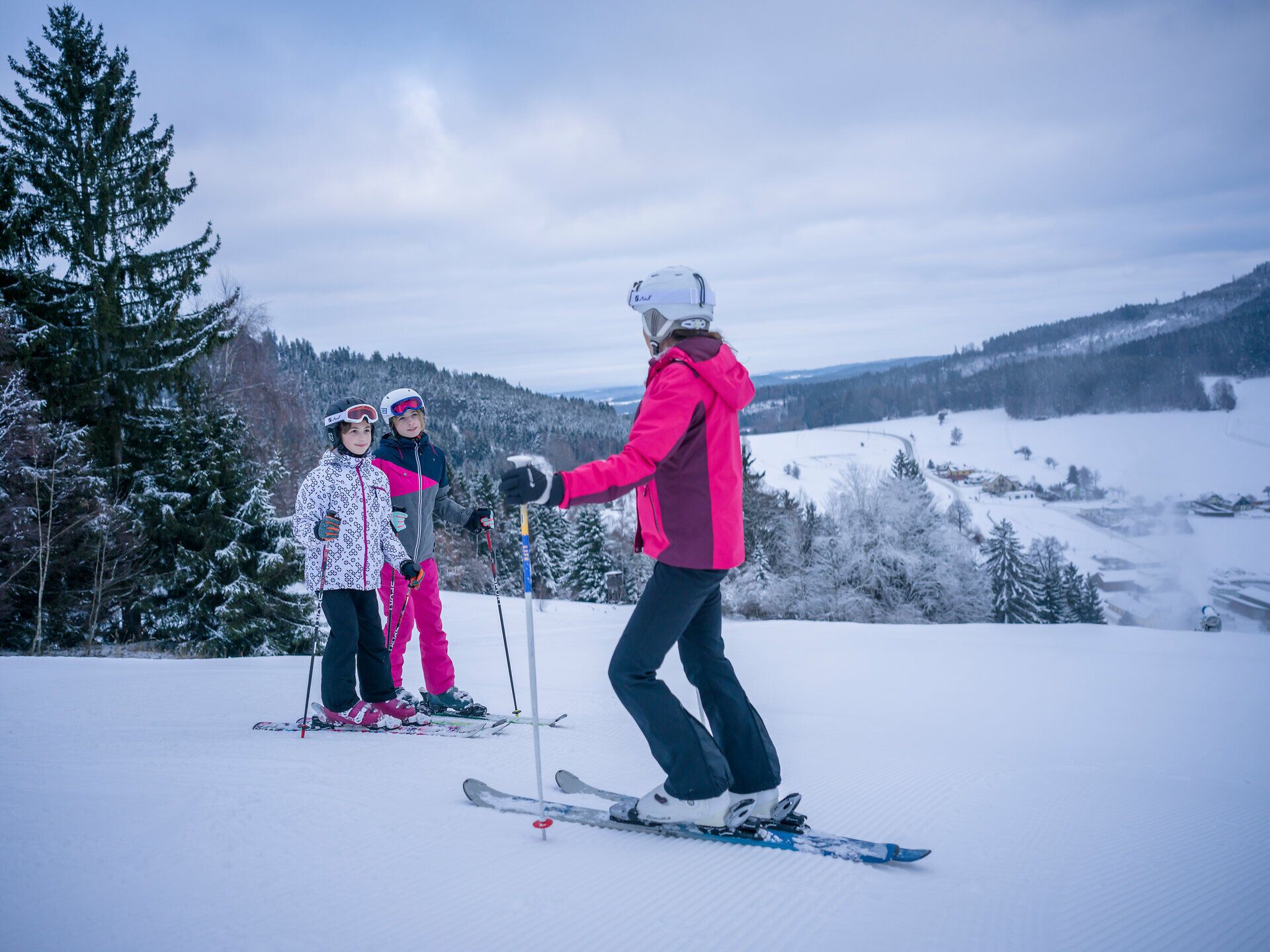 Eine Familie genießt den Winterzauber beim Skifahren in der malerischen Landschaft des Waldviertels. Die schneebedeckten Pisten laden zu fröhlichen Abfahrten ein, während die frische Bergluft für unvergessliche Erlebnisse sorgt.