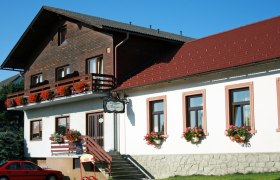 Gasthaus Malzer mit Blumen geschmücktem Balkon und Fenstern.