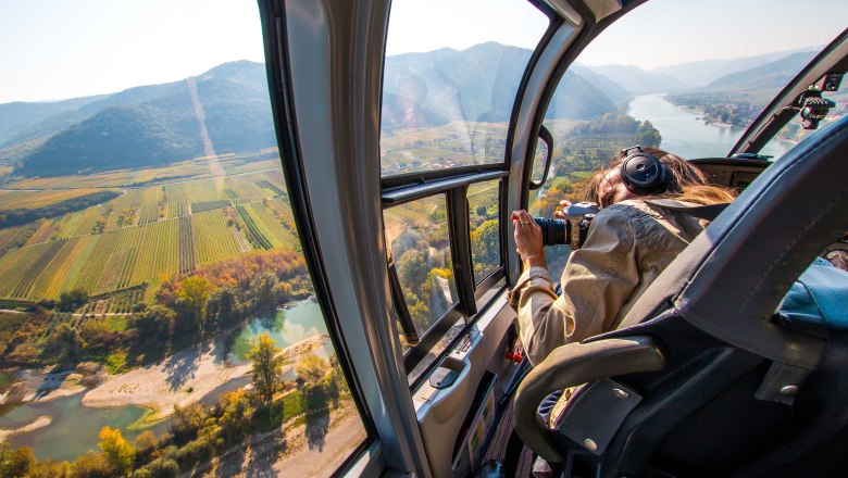 Blick aus einem Helikopter auf eine Landschaft mit Fluss und Feldern.