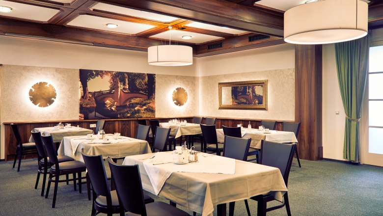 Elegant restaurant with laid tables, modern lighting and wall decorations.