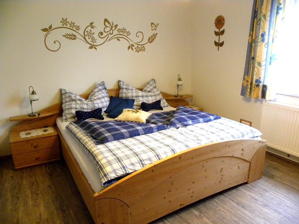 Gemütliches Schlafzimmer mit Holzbett und blauer Bettwäsche.