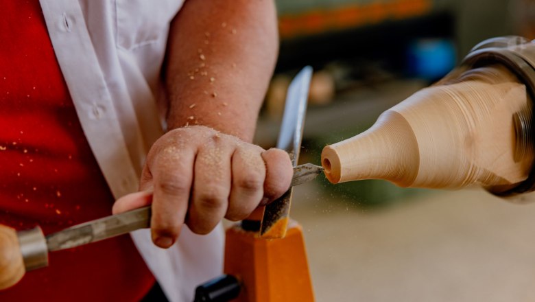 Nahaufnahme einer Person, die Holz auf einer Drechselbank bearbeitet.