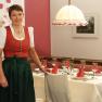 Eine Frau in traditioneller Kleidung steht neben einem gedeckten Tisch in einem Restaurant.
